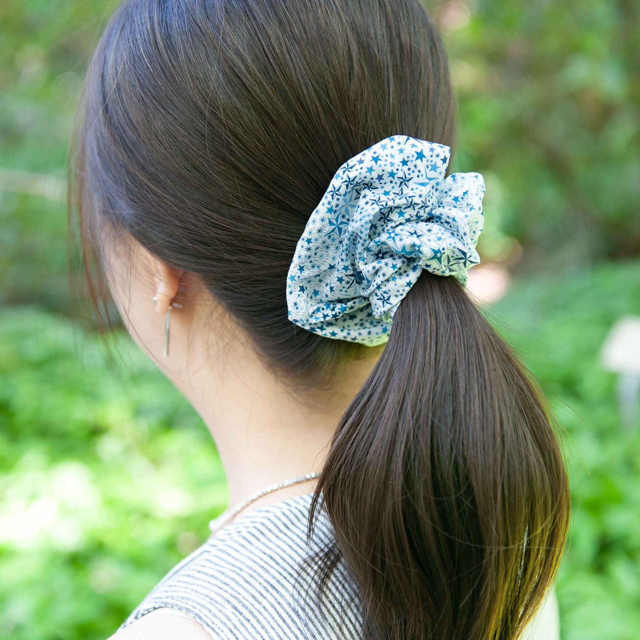 a woman wearing a blue star print liberty fabric scrunchie for ponytail