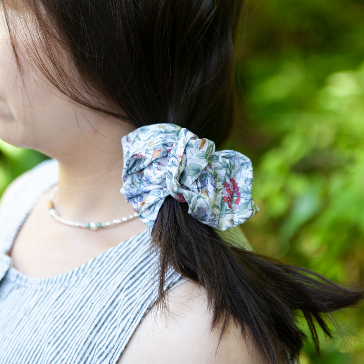 a woman wearing a liberty fabric scrunchie for a side ponytail