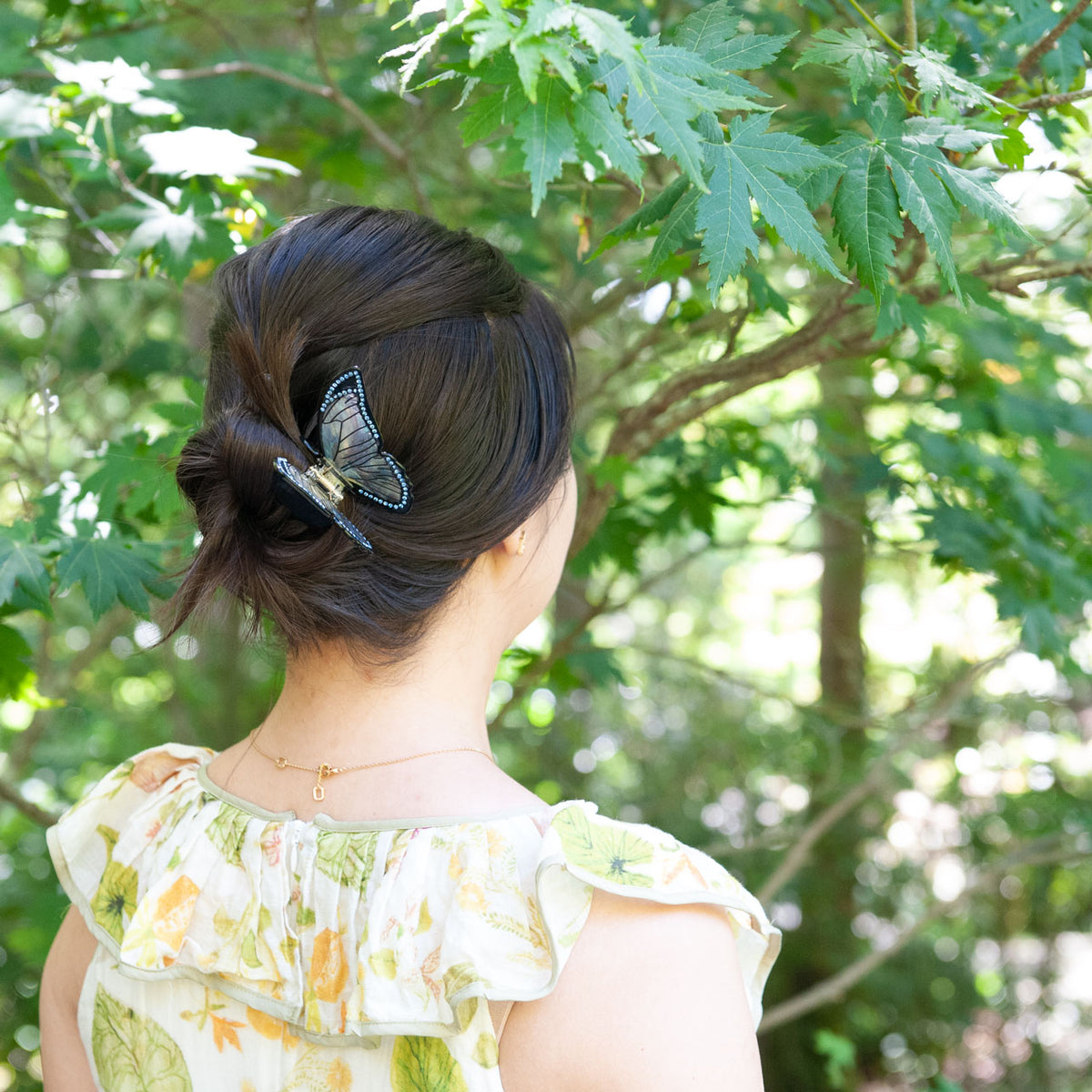 Black butterfly claw clip with iridescent wings accessorizing a bun hairstyle.