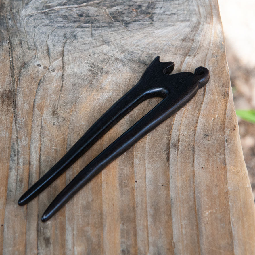 an ebony wooden cat hair pin with a small cat design and curled tail