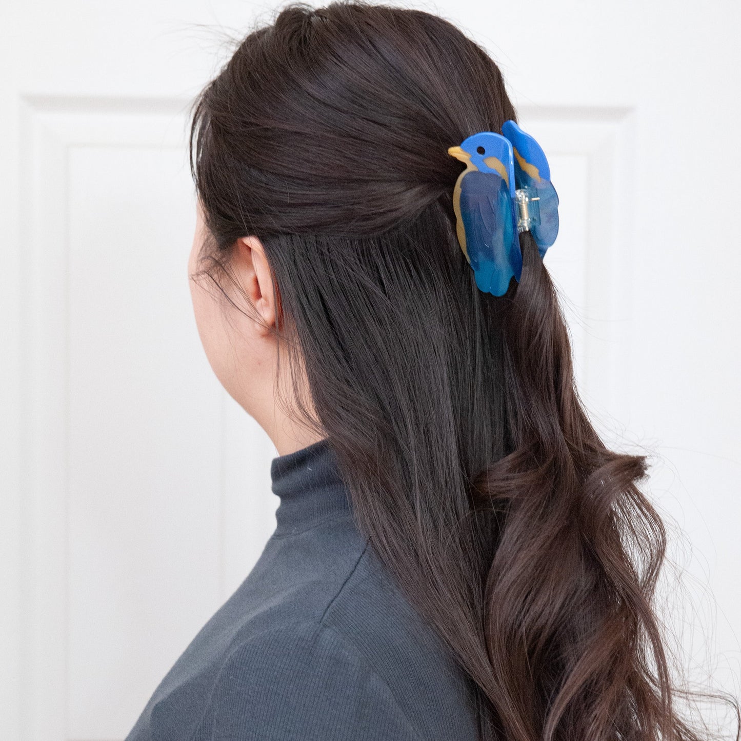 a woman wearing a blue bird hair clip for half up half down hairstyle