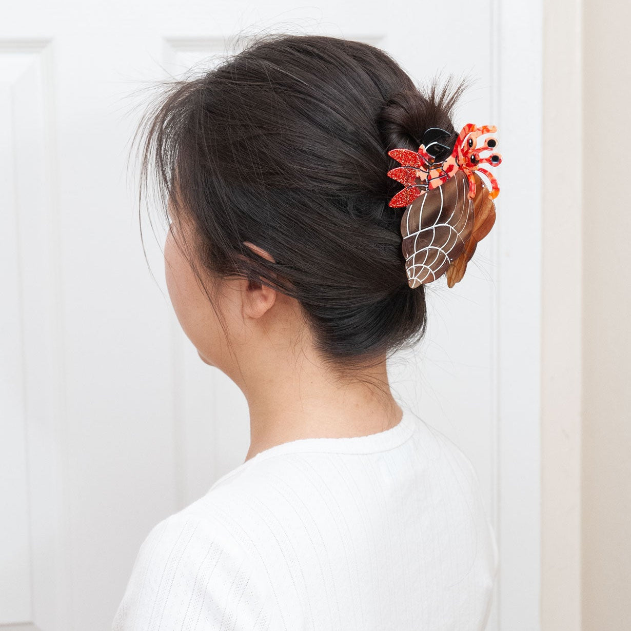 A woman shown from the back wearing a hermit crab claw clip for a full up hairstyle.