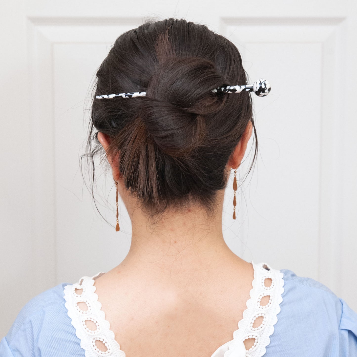 a woman wearing a long hair stick for full updo