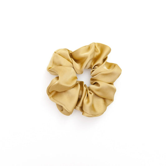 A collection of vibrant satin scrunchies in various colors, displayed neatly on a white surface. The scrunchies are soft and glossy, showcasing their luxurious texture and elegant appeal.