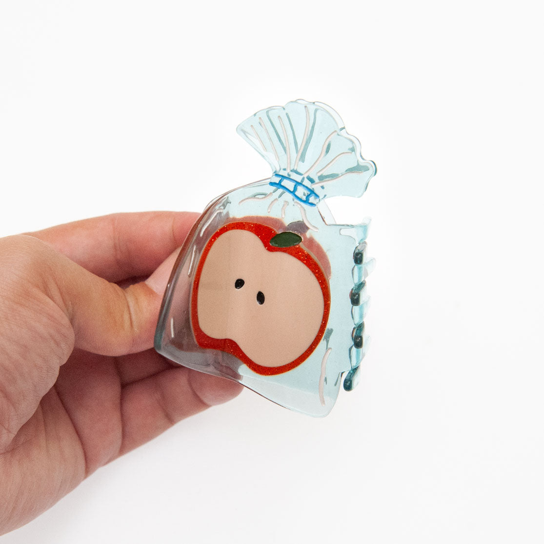 Hand holding a small clear bag with a cute apple design on a white background