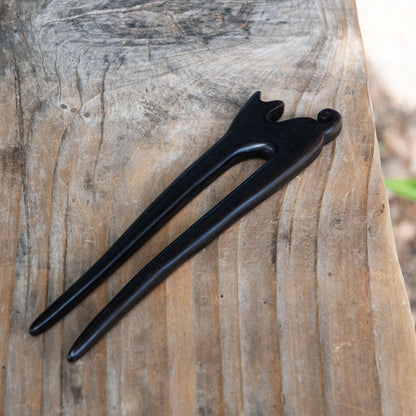 an ebony wooden cat hair pin with a small cat design and curled tail