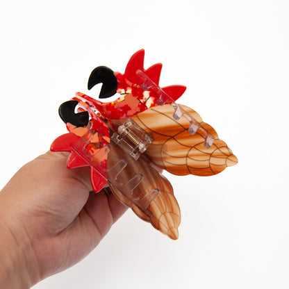 A hand holding a decorative hermit crab claw hair clip.