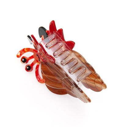 A translucent brown and red hermit crab shaped hair claw clip on a solid white background.
