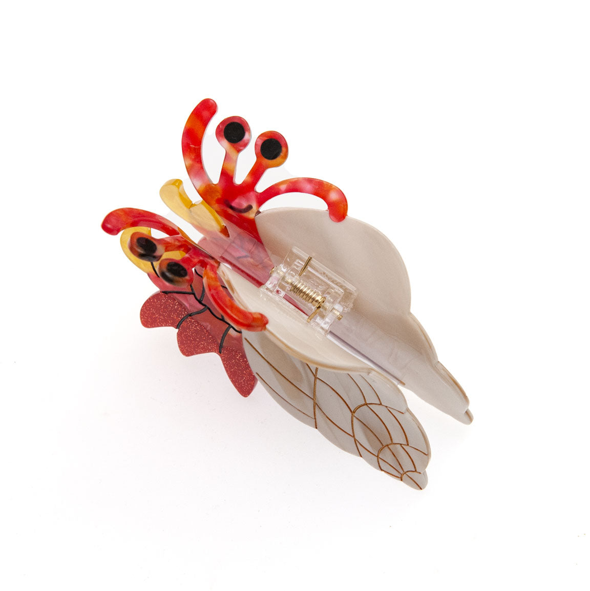 A whimsical hair claw clip shaped like a hermit crab, featuring a cream-colored shell, red and orange striped legs, and glittery red accents, set against a plain white background.