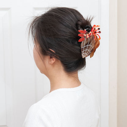 A woman shown from the back wearing a hermit crab claw clip for a full up hairstyle.