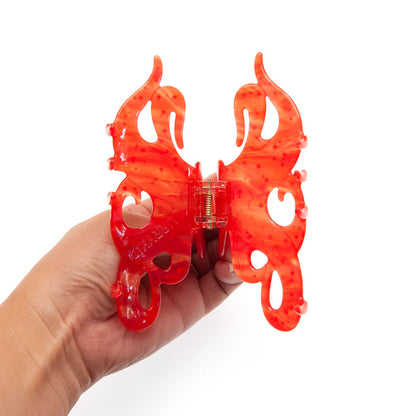 Hand holding a red octopus claw clip to show its painted details