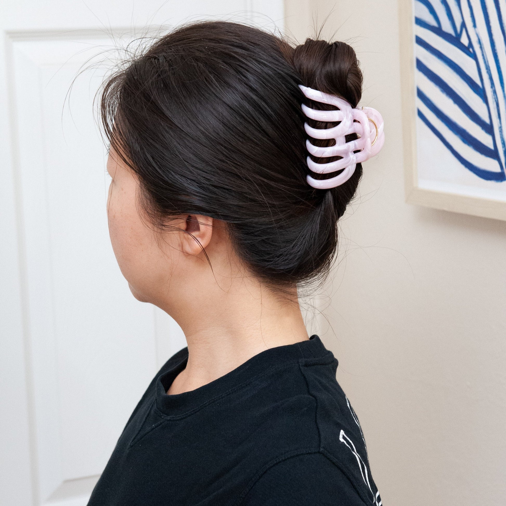 a woman wearing an extra large claw clip in baby pink