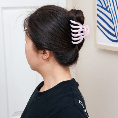 a woman wearing an extra large claw clip in baby pink