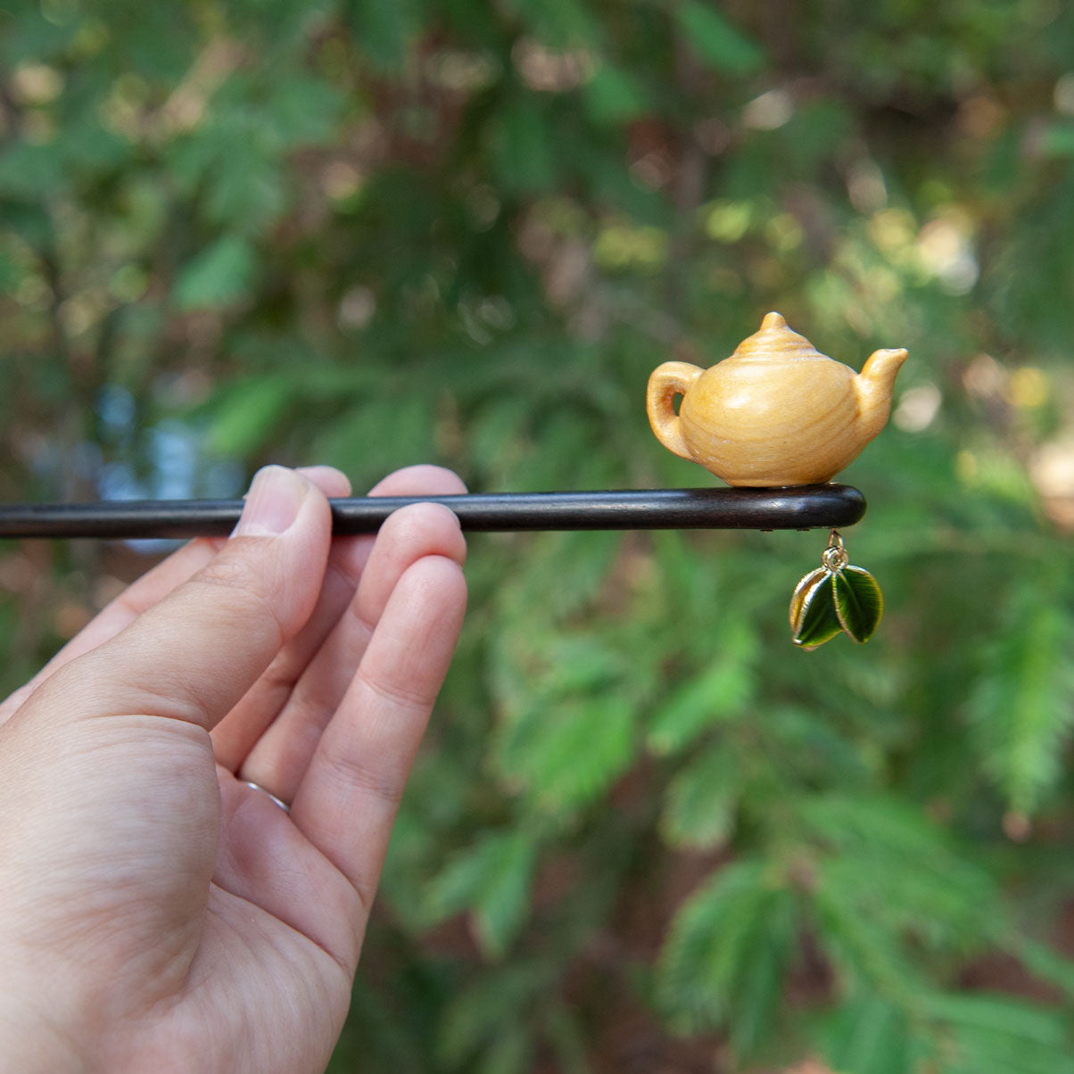 Handmade wooden hair stick featuring a small peach wood teapot and two delicate tea leaves at the end